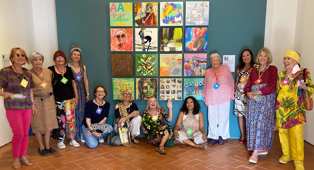 Twelve of the 15 artists at the entrance to the gallery, in front of the AAN logo, an introduction to the show made up of artworks by each of the artists