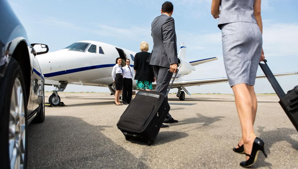 Business partners with luggage walking towards private jet at terminal
