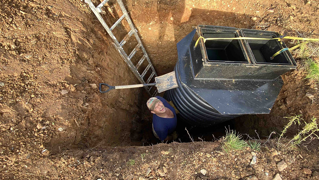 Digging in – Alastair over his head trying to get a new water tank level while pondering the houses on the hill