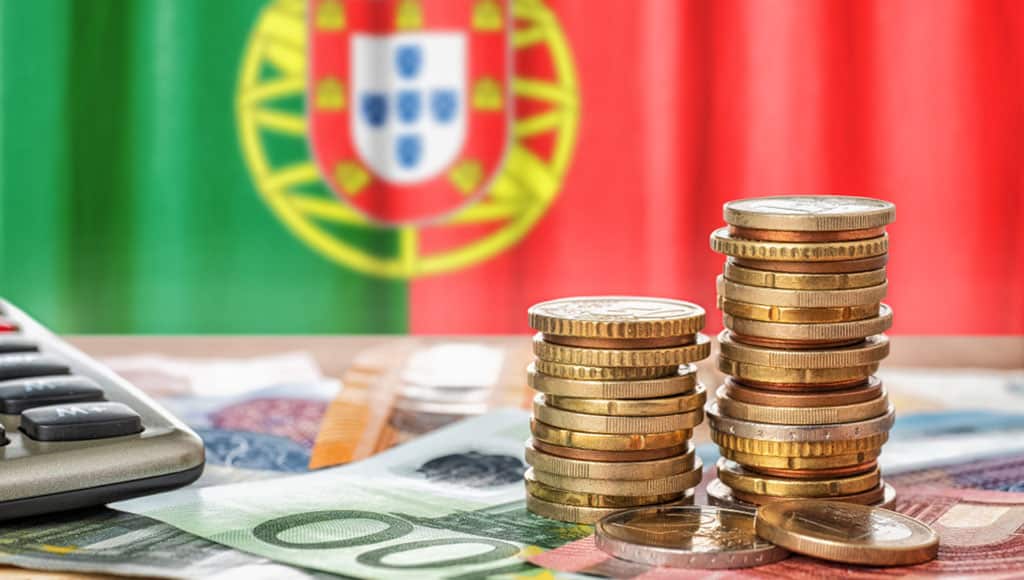 Euro banknotes and coins in front of the national flag of Portugal