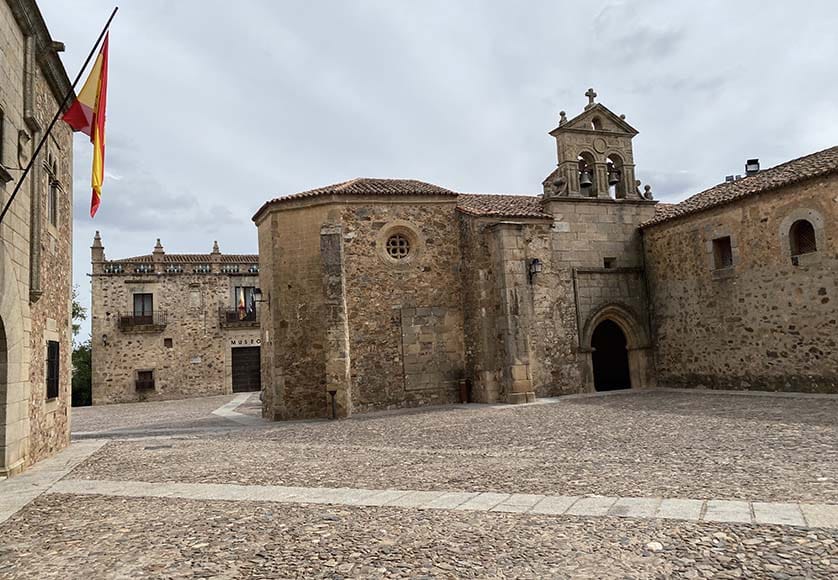 Looking across the Plaza San Pablo, past the Convento de San Pablo, with the Plaza de las Veletas and the Museo Provincial in the background|One of the many narrow alleys in old Cáceres, a perfect reason why there are no cars in most of the town|The Plaza de San Jorge with the Palacio de los Golfines de Abajo, which dates from the late 15th century and has always been in the hands of the Golfin family|Looking across the Plaza de San Jorge at the baroque 18th century Iglesia de San Francisco Javier (there is a great view from the towers)|The Plaza de los Golfines, with the Palacio de los Golfines de Abajo on the left and the baroque façade of the Edificio del Ministerio de Fomento (Ministry of Public Works) on the right.|A statue of San Pedro de Alcántara, standing in a niche at the corner of the cathedral. Rub his toes and you will have good luck!|The portals of the cathedral are Gothic, and in the Evangelio Portal, there is a corbelled pillar holding a rather sweet statue of the Virgin and Jesus.|The Plaza de Santa Maria and the Catedral de Santa Maria, the most important church in Cáceres, built at the end of the 15th century. There’s another great view from the tower.|The 15th century gothic and renaissance Casa del Sol built for the Solis family, whose coat of arms, featuring a great sun with a human face crowned with a helmet, appears above the front door.|The gothic 16th century Iglesia de San Mateo was made a Monumento Histórico Artístico in 1982. It is a sort of Panthéon of Cáceres in which the noble families of the town (Ovando, Golfines, Paredes, Saavedra) are buried.|The Convento de San Pablo, founded in the 15th century, in the Plaza de San Mateo.|The Palacio de las Cigüeñas (storks) was built in the 15th century by Don Diego Ovando on the highest point in the town. The tower is the only one left standing by Queen Isabella in 1477 – it has great views. Inside the Palacio is a military museum.|Helga is standing on our balcony in the Parador of Cáceres, looking forward to a cold glass of blanco from La Mancha and a lovely dinner.|The portal of the Iglesia de San Mateo, with Saints Peter and Paul in the lateral medallions and Saint Matthew above.