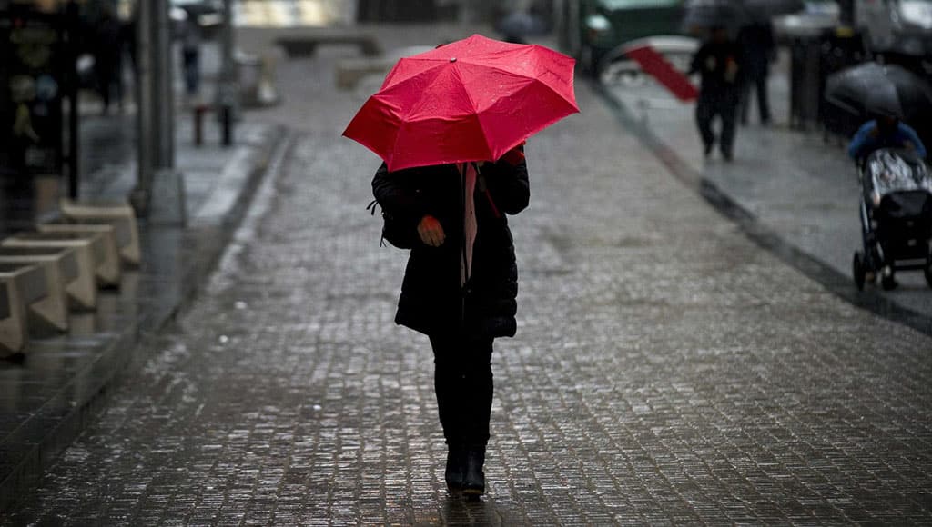 woman walking outdoors holding a red umbrella