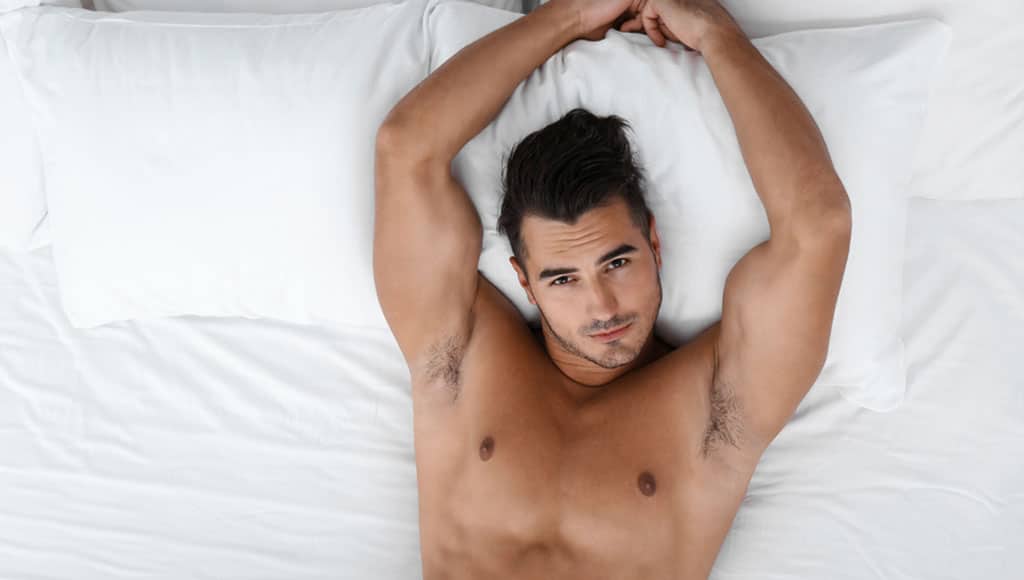 Sexy young man lying on bed with soft pillows at home, top view|Home Comforts 1