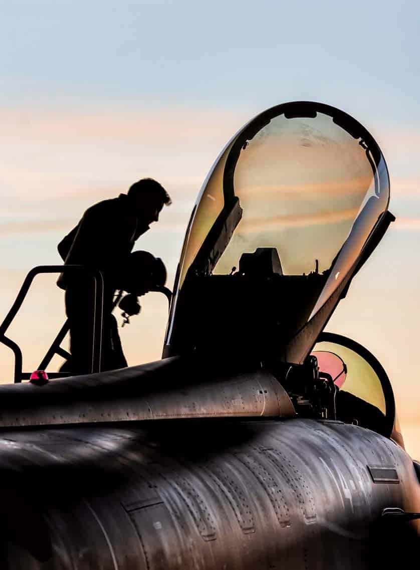 Military pilot boarding his fighter plane at sunset