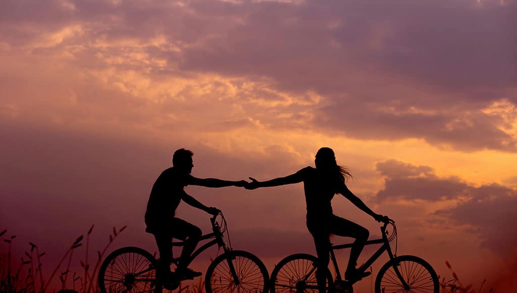 couple cycling and holding hands