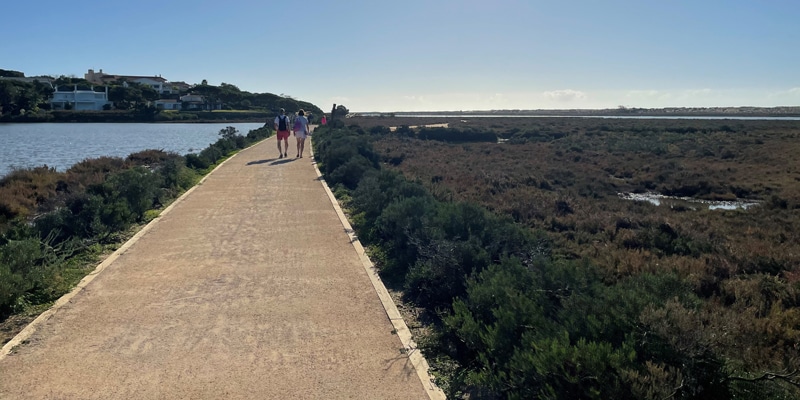 Couple walking on a pedestrian road by the Ria Formosa in the Algarve