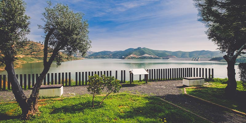 Photo of the Odelouca dam, in one of the municipalities taking part in the Águas Sem Fronteiras project|Poster for the Águas Sem Fronteiras project and photo of Teresa Fernandes, Head of Communications and Environmental Education at Águas do Algarve