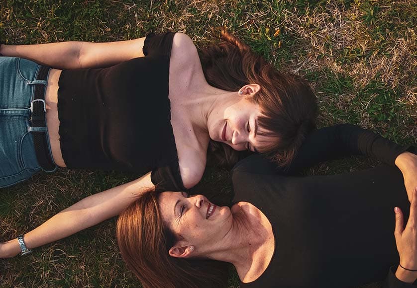 two women lying on grass floor