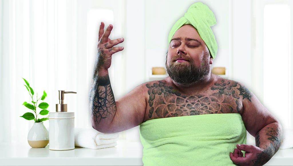 Relaxed pleased fat man in white towel standing isolated on the grey background and smiling with his eyes closed while putting one hand up