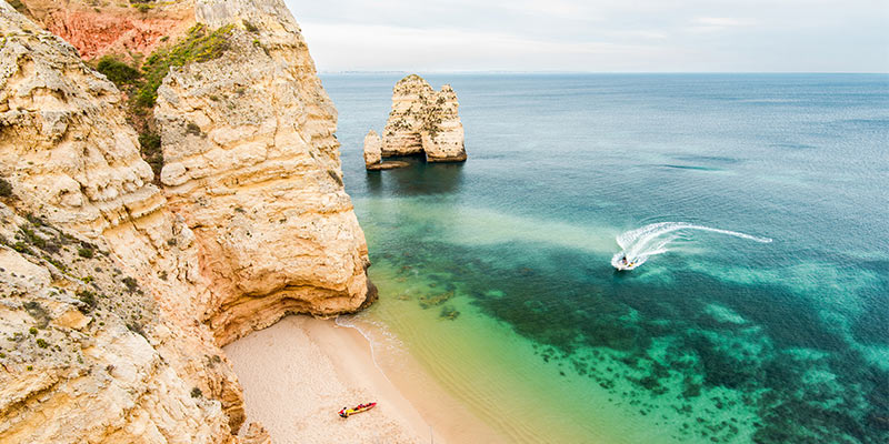 Photo of a beach in the Algarve where UK expats love to live|Photo of Manuela Robinson, Associate Director at the|
