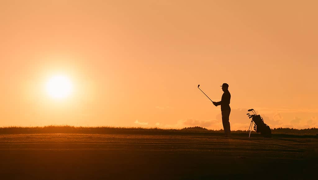 Man playing golf at sunset
