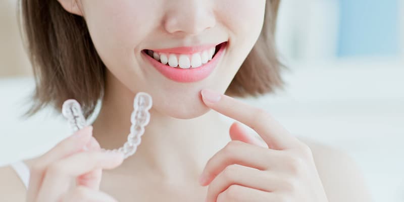 Woman holding an invisible dental brace such as the ones they use at Vita Centro Clinics