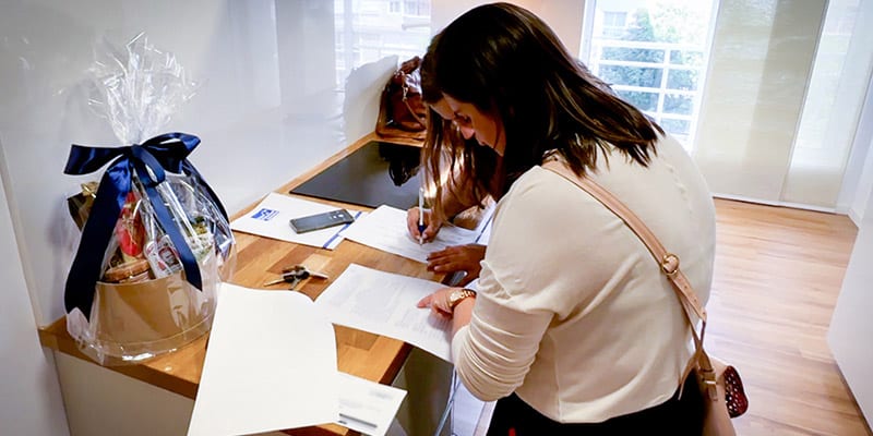A woman filling out paperwork for a moving process|Photo of a roll-up with Global International Relocation's contact information