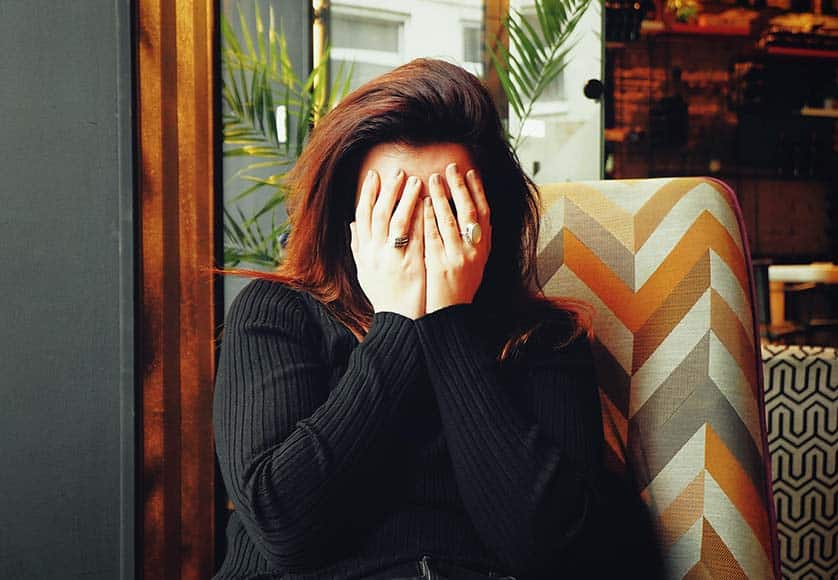 woman with hands covering face
