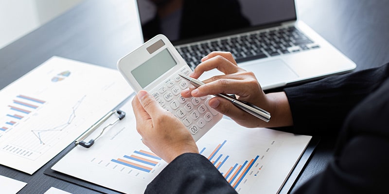 Hands od a man using a calculator and looking at financial reports like JS Advisers does|Partial image of a man holding a smartphone