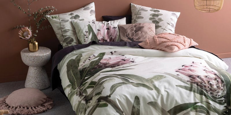 Photo of a bed with beautiful flowery linen||