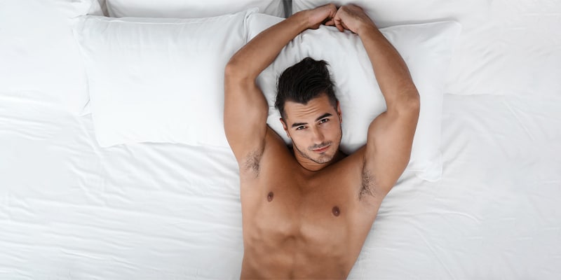 Photo of a man laying in a bed with white linen