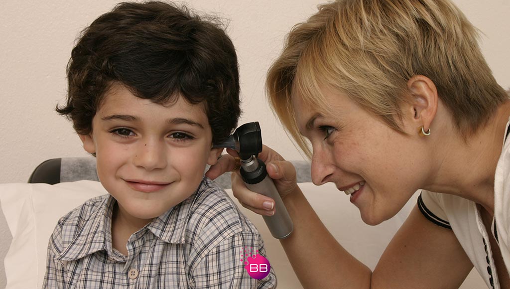 Dr Joanna Karamon, Clinical Director of LuzDoc and Medilagos looking into a young patient's ear|doctor|A tablet with a patient's medical data to symbolise the holistic approach used by Medilagos