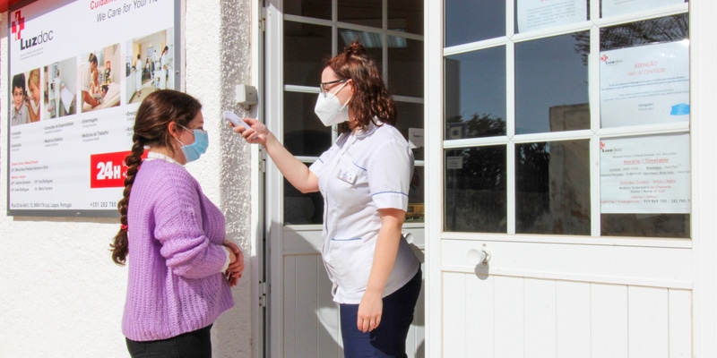 Luzdoc staff taking a patient's temperature before entering the building
