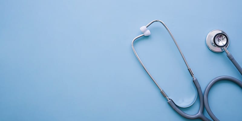 Partial image of a stethoscope to illustrate healthcare and health insurance|Photo of Medal's logo on the wall of their Portimão office