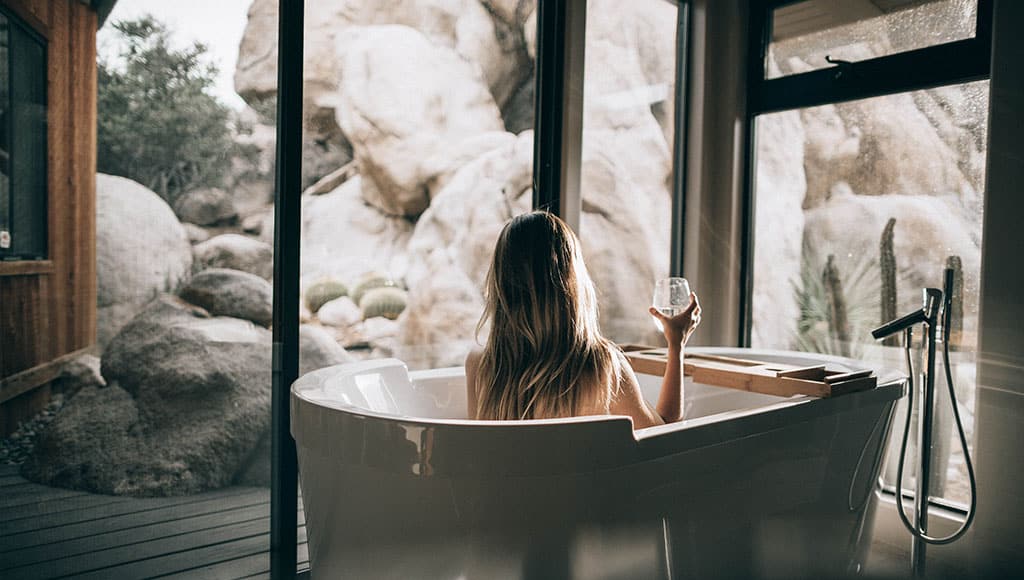 woman relaxing in bathtub with a glass of wine