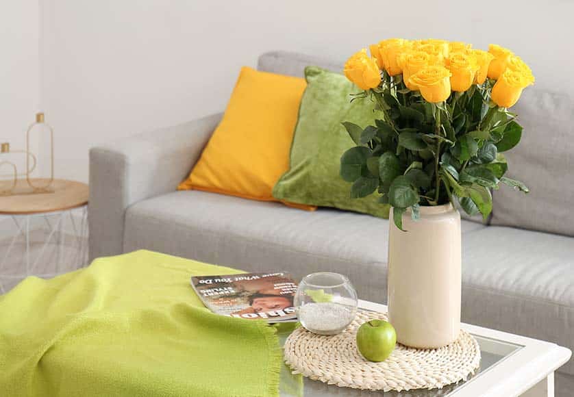 Vase with beautiful yellow roses on table in living room|Towels are on bed. White bedding close-up. Clean terry towels on bedstead. Concept - bed linen at hotel. Sewing industry. Several towels lie on in a pile. Sale of sets with bed linen. Textile