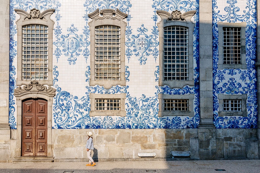 Tourist walking, azulejos tiles over Chapel Of Souls, Porto, Portugal