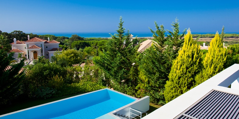 View of a pool from the terrace of a luxury villa in Vale do Lobo, one of the Algarve resorts feeling the rise in real estate investement||Aerial view of Vale do Lobo resort who felt a rise in real estate investment throughout 2020 and 2021|Aerial view of one of Vale do Lobo's golf courses who has been feeling a rise in real estate investment throughout 2020 and 2021