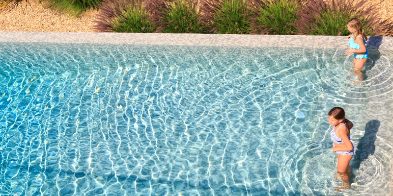 Two girls entering a pool on a property to simbolize the rise in real estate investment in Portugal