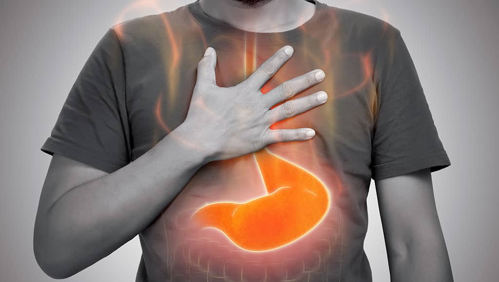 A man burning sensation in chest from acid reflux on gray background.