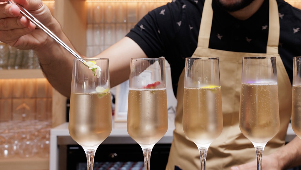 A chef putting edible flowers in champagne glaces at Vale do Lobo resort