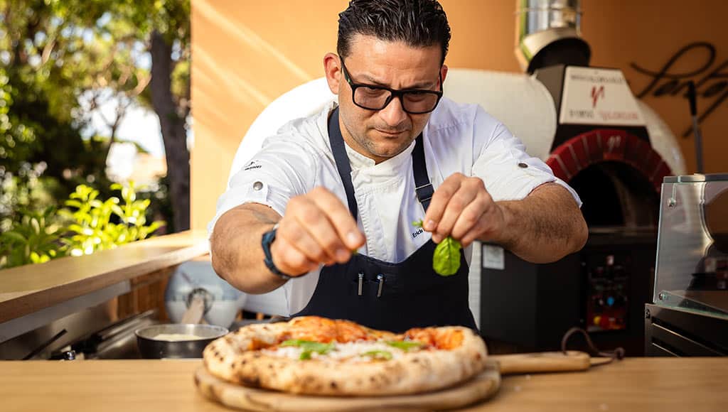 The chef at Pine Cliff's Portofino by Mimo restaurant seasoning a pizza
